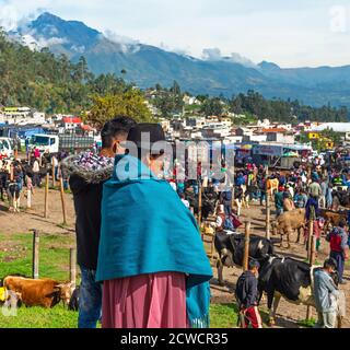 Indigenous Ecuadorian Otavalo woman with son looking over the animal market of Otavalo with the Cotacachi volcano in the background, Ecuador. Stock Photo