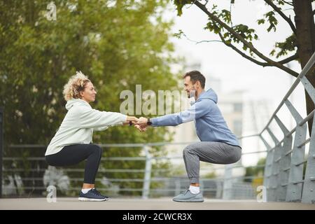 Young healthy couple holding hands and exercising during training in the park Stock Photo