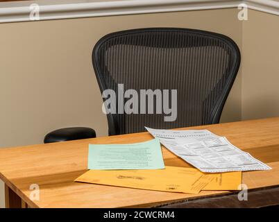 Empty home desk and chair with paperwork for completing the mail-in or absentee ballot for the 2020 presidential election Stock Photo