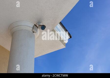 Surveillance cctv (closed circuit television) camera installed on roof of private house on blue sky background for protection against crime. Bottom vi Stock Photo