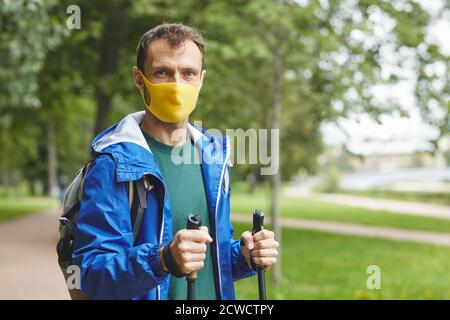 Portrait of young man in protective mask looking at camera while walking in the park Stock Photo