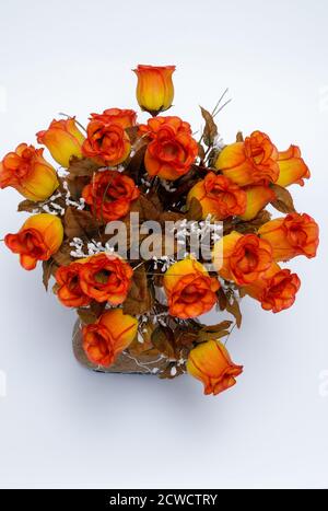 roses, colorful artificial flowers in a decorative vase on a light background Stock Photo