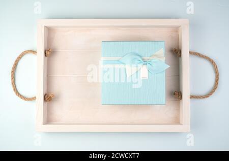 Soft blue gift box with a bow on a white tray. Stock Photo