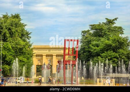 Geneva, Switzerland - Aug 16, 2020: Broken Chair with fountains and children playing with splashing water, sculpture in Place des Nations in front of Stock Photo