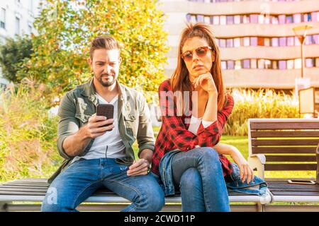 A girlfriend being annoyed by her boyfriends smartphone usage and bored. Stock Photo