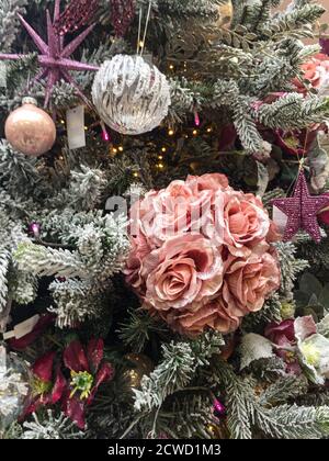 Decorations on Christmas tree including pink roses, stars and baubles. Stock Photo