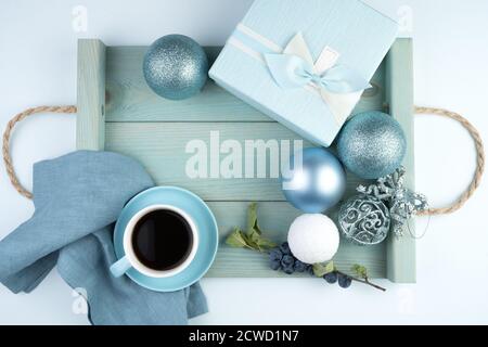 Happy new year 2021, festive composition with a Cup of coffee, gift box, Christmas balloons and a tray in a soft blue color. Stock Photo