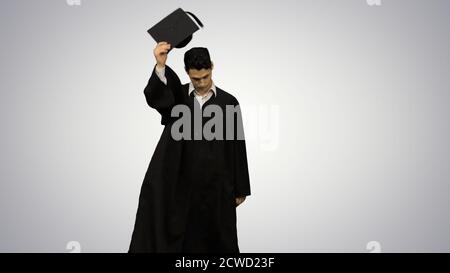 Male graduate walking in the frame, throwing his mortarboard and Stock Photo