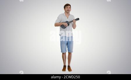Smiling young man playing ukulele and singing looking into the c Stock Photo