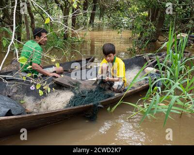 A young boy picking catfish from his net on Belluda Creek, Ucayali River, Loreto, Peru. Stock Photo