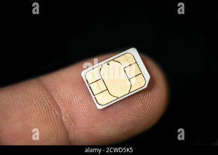 Isolated nano sim card on human finger over black background,hi tech smartphone Stock Photo