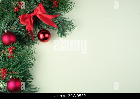 Decorated with red Christmas toys, bows and glass balls, pine branches on a light green background. Stock Photo