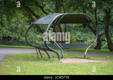 Boultham Park, park bench, picnic shelter, metal construction, oval shape, open spaces, Lincoln, trees, footpaths, outdoors, space-age, greenery. Stock Photo