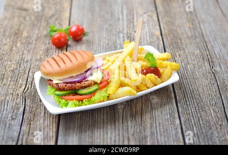 Delicious cheeseburger and chips with ketchup served in a reusable snack bar bowl on a wooden background Stock Photo