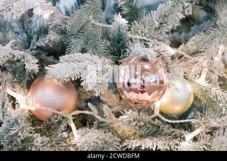 Balls and garlands hanging on pine branches on festive backdrop. Golden baubles on spruce tree. Christmas background. Merry Christmas and Happy New Stock Photo