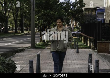 Portrait of a young man using his smartphone while walking down the street Stock Photo