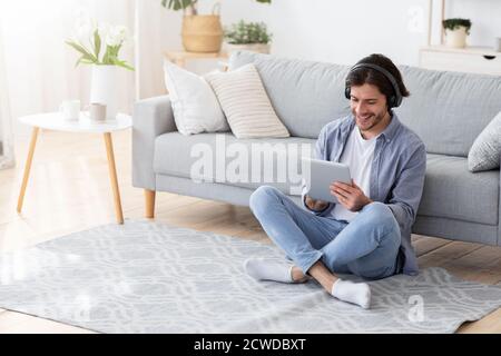 Happy young man using wireless headset and digital tablet Stock Photo