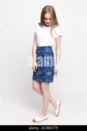 cute young slender woman in a white t-shirt and denim fashionable skirt on a white background. concept of advertising photo for once Stock Photo