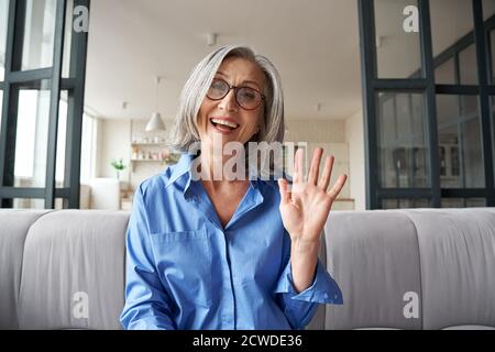 Happy mature woman online teacher talking to web cam video calling. Stock Photo