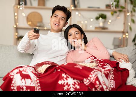 Japanese Couple Watching TV On Christmas Eve Sitting At Home Stock Photo