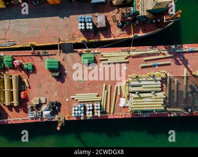 Aerial view of floating cargo transportation by construction materials transported building pipes and metal structures on barges Stock Photo