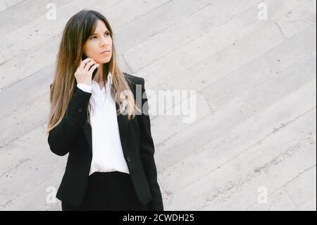 Upset Businesswoman talking on telephone standing outside office building. Social family, business and communication problem concept. High quality photo Stock Photo