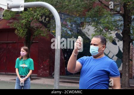 New York, New York, USA. 28th Sep, 2020. The bell rang at 294 Public School in the Bronx where children returned to school like 300,000 elementary students in New York City after six months of closure. A masked-face school assistant checks the temperature tester before using it for each child as the doors have just opened. Nevertheless, back to school could be questioned again as the Covid-19 reappeared in several boroughs. In addition, many parents and teachers are contesting the back-to-school program set up by the mayor Bill de Blasio, believing that the health measures are not safe en Stock Photo