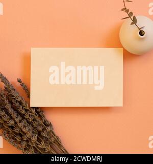 Blank memo pad, empty paper with lavender dry flowers and eucalyptus flowerpot on coral background. flat lay, top view, copy space Stock Photo