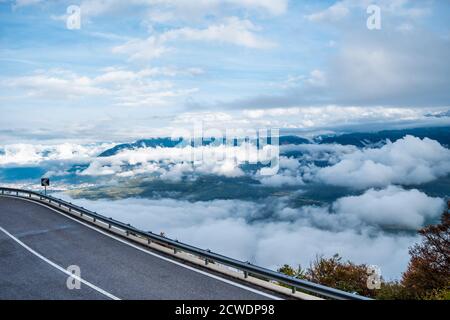 Road along some valley somewhere in northen Italy with cloudy sky. Stock Photo