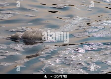 A clump of foam is floating on the surface of soapy-looking river water. Stock Photo