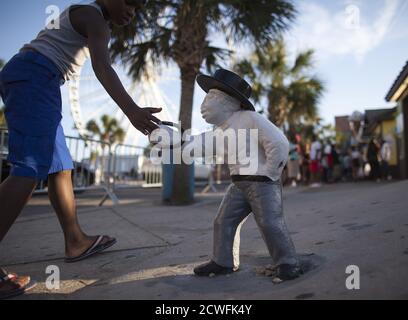 A boy touches an old lawn jockey that has been painted white on Ocean Boulevard during the 2015 Atlantic Beach Memorial Day BikeFest in Myrtle Beach, South Carolina May 24, 2015. After three people were killed and seven wounded in shootings during 2014 Bikefest, State officials called for an end to the event that draws thousands to the family-friendly beach town. Their efforts were unsuccessful. Bikers returned to Myrtle Beach - just a week after a bloody motorcycle gang shootout in Waco, Texas. But this time authorities are more prepared, with dozens of new surveillance cameras and a police f