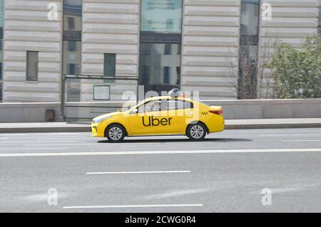 Yellow taxi with Uber logo badge on city streets Stock Photo