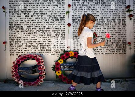 A girl holds flowers as she walks in front of a memorial wall, engraved with names of fallen Israeli soldiers, after a ceremony marking Memorial Day at the Israeli army's Armoured Corps' Memorial in Latrun, near Jerusalem April 15, 2013. Israel on Monday marks Memorial Day to commemorate its fallen soldiers. REUTERS/Amir Cohen (ISRAEL - Tags: ANNIVERSARY MILITARY POLITICS CONFLICT TPX IMAGES OF THE DAY)