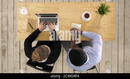 Two colleagues discussing data on laptop putting down notes Stock Photo