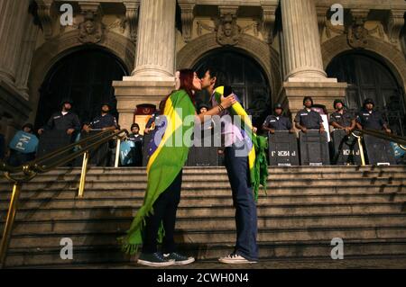 Two demonstrators kiss each other in front of police officers during a protest in central Rio de Janeiro June 27, 2013. Tens of thousands of Brazilians have taken to the streets this month in the biggest protests in 20 years, fuelled by an array of grievances ranging from poor public services to the high cost of World Cup soccer stadiums and corruption. REUTERS/Pilar Olivares(BRAZIL - Tags: POLITICS CIVIL UNREST SPORT)