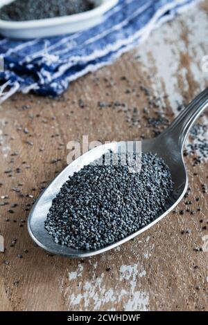 Poppy seeds in a spoon on rustic background Stock Photo