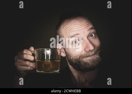 A friendly guy smiles at the camera and offers tea. Stock Photo