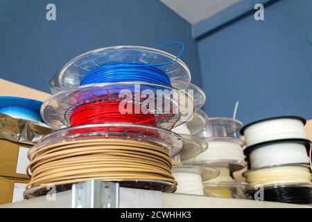 Stacks of 3d printing filament in different colors lying on metal shelf Stock Photo
