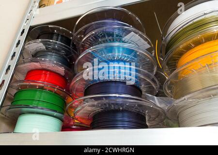 Stacks of 3d printing filament in different colors lying on metal shelf Stock Photo