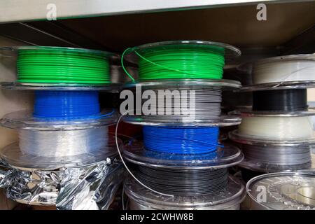 Stacks of 3d printing filament in different colors lying on metal shelf Stock Photo