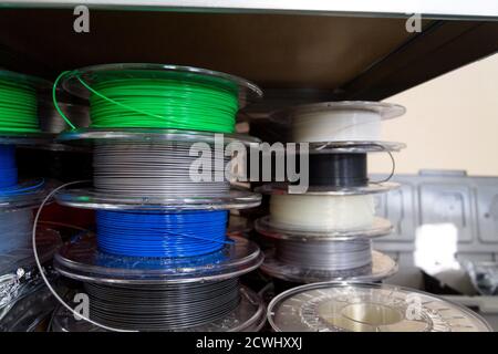 Stacks of 3d printing filament in different colors lying on metal shelf Stock Photo