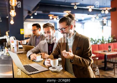 Happy young attractive business man friends talking in cafe urban Stock Photo