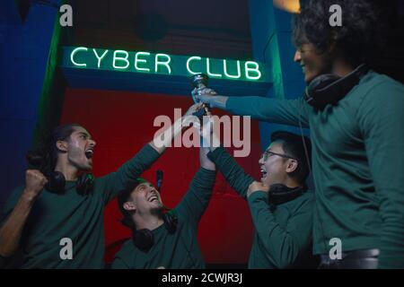 Excited group of gamers taking part in a computer game competition they winning the cup together Stock Photo