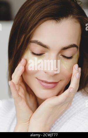 Closeup portrait of beautiful young woman with closed eyes applying eye patches. Stock Photo