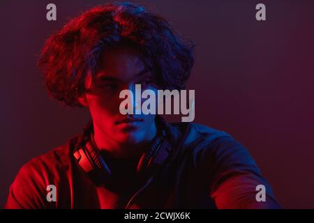 Close-up of young gamer in headphones playing computer games in dark room Stock Photo