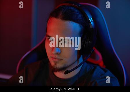 Young computer programmer in headphones working on computer in dark office Stock Photo