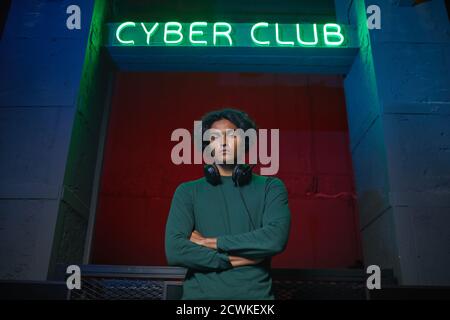 Portrait of young man standing with arms crossed and looking at camera standing near the cyber club Stock Photo