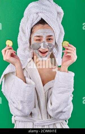 Woman with clay mask holding cucumber slices. Stock Photo