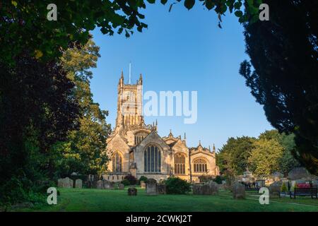 The Church of St. John the Baptist from the garden of rememberance at sunrise in autumn. Cirencester, Cotswolds, Gloucestershire, England Stock Photo