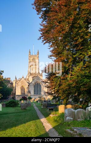 The Church of St. John the Baptist from the garden of rememberance at sunrise in autumn. Cirencester, Cotswolds, Gloucestershire, England Stock Photo